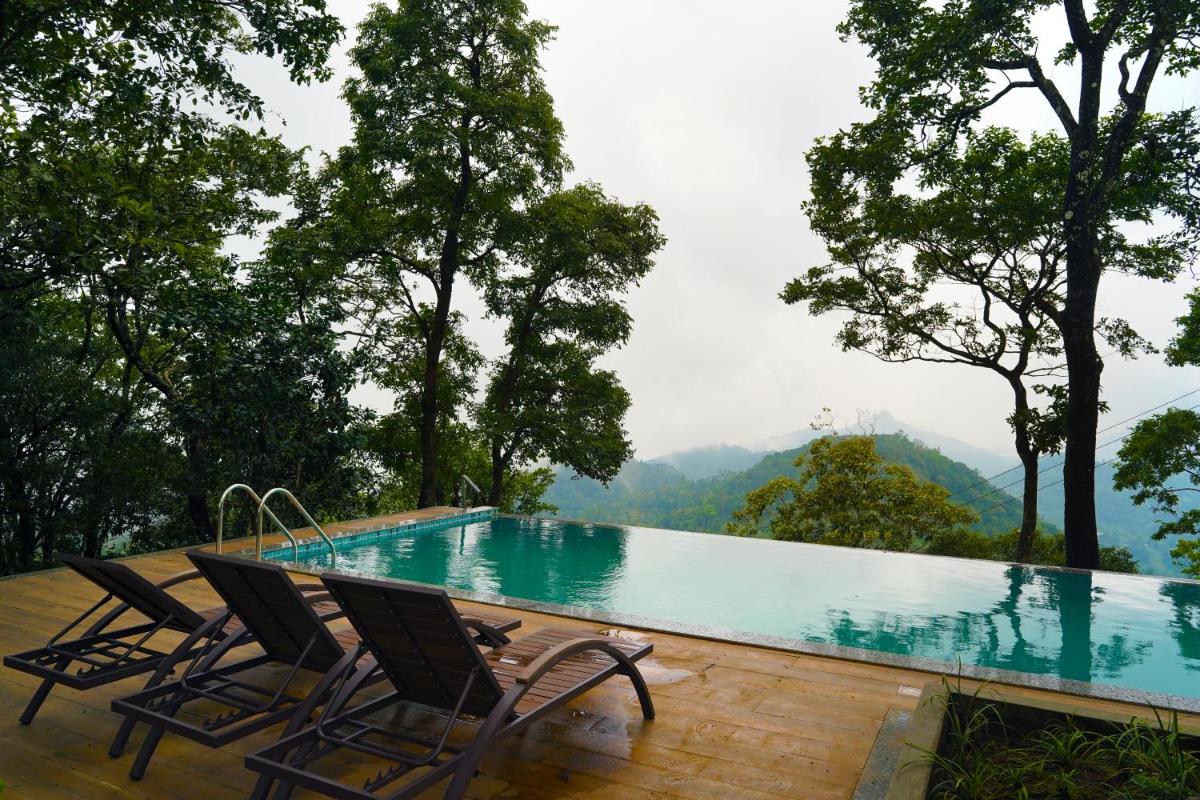 a pool with chairs and a view of a mountain at Elephant Passage in Munnar a pool with chairs and a view of a mountain at Elephant Passage in Munnar