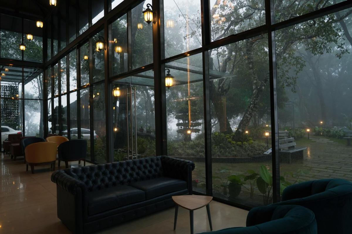 a living room with a couch and a large window at Elephant Passage in Munnar