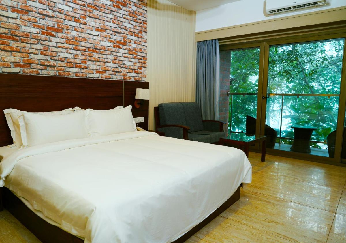 a bedroom with a white bed and a brick wall at Elephant Passage in Munnar