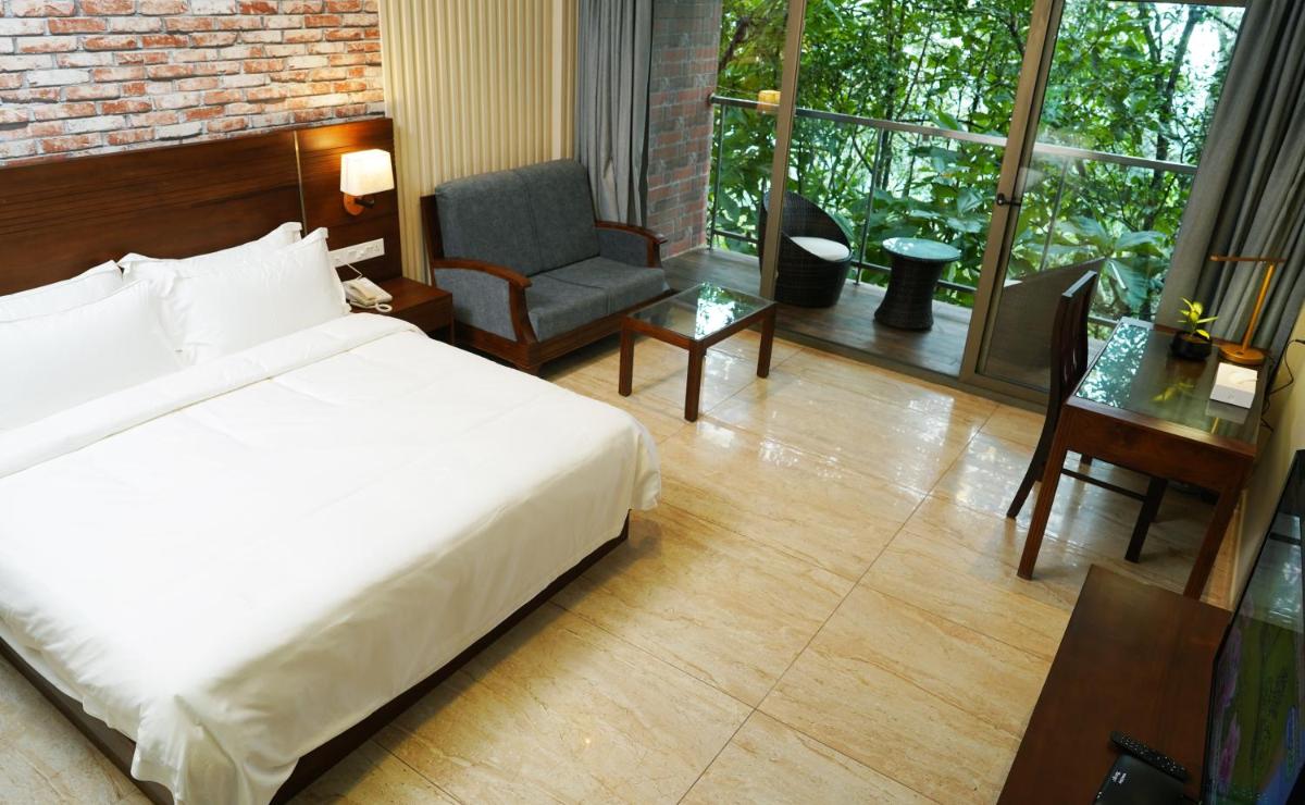 a bedroom with a bed and a desk and a chair at Elephant Passage in Munnar