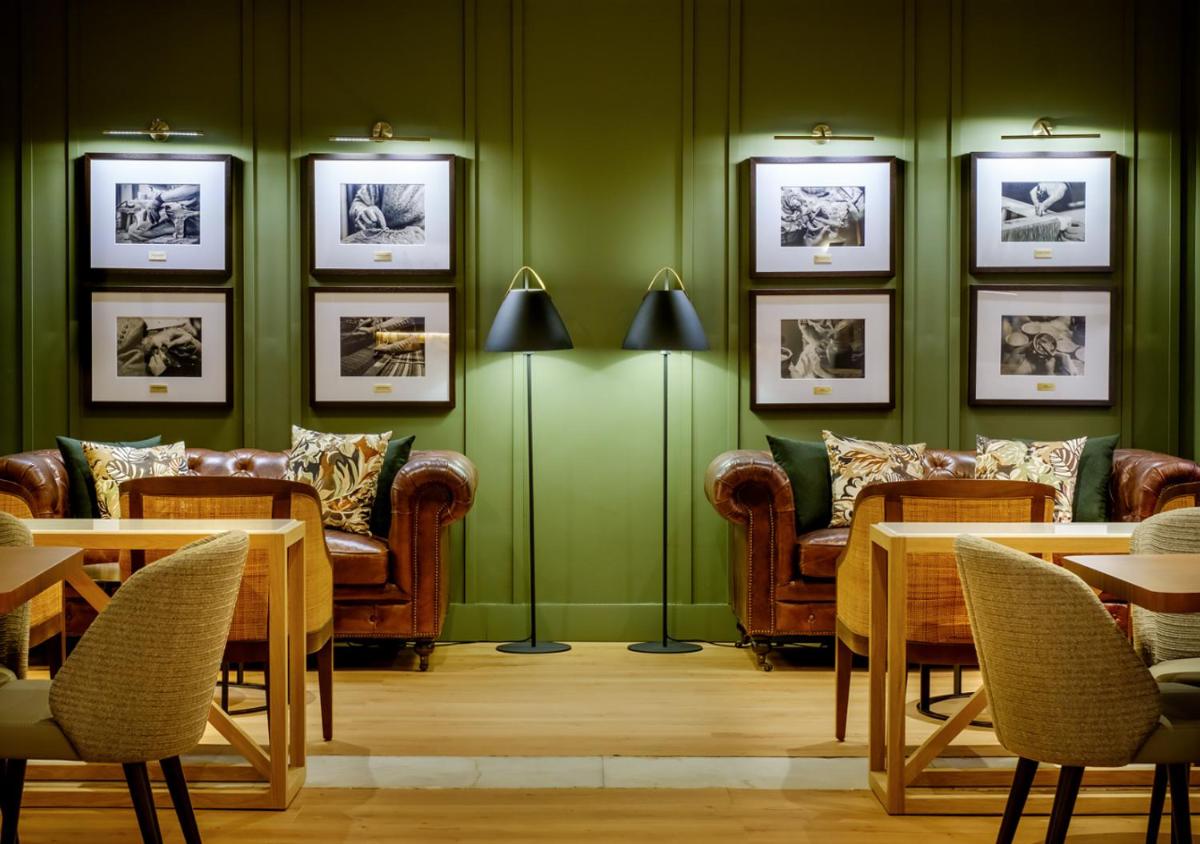 um restaurante com sofás, mesas e quadros na parede em Evora Hotel em Évora