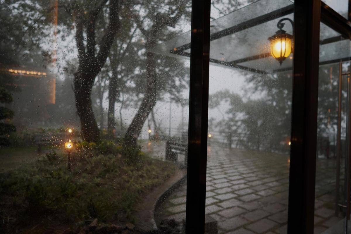 a window with a view of a street in the rain at Elephant Passage in Munnar