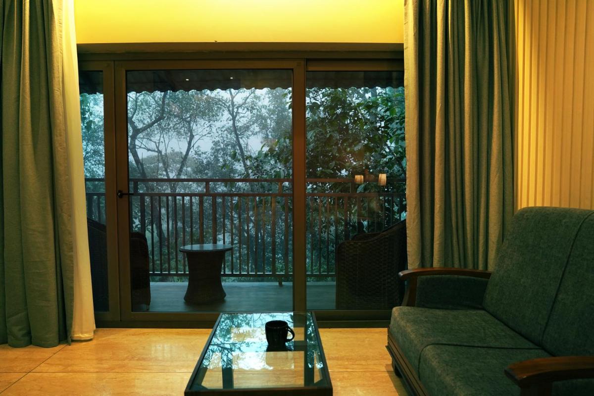 a living room with a couch and a glass table at Elephant Passage in Munnar