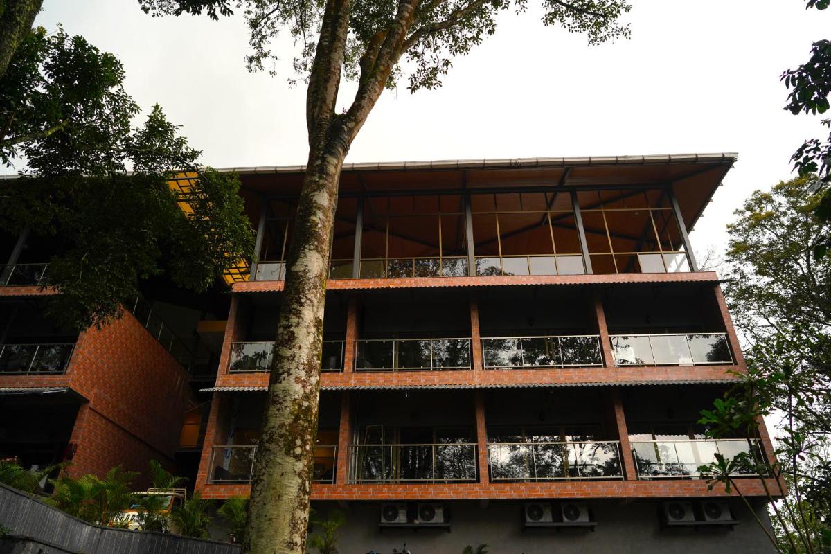an apartment building with balconies and a tree at Elephant Passage in Munnar