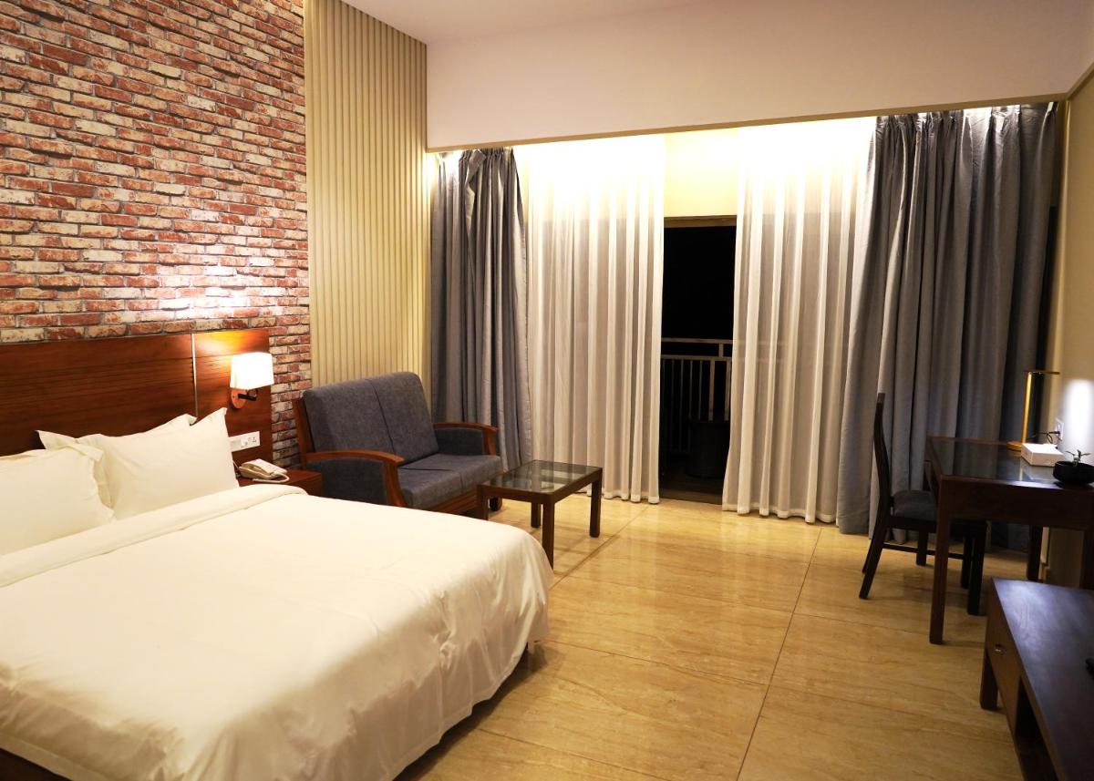 a hotel room with a bed and a chair and a desk at Elephant Passage in Munnar