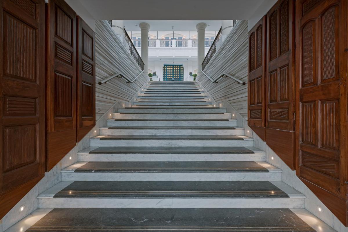 a stairway in a building with wooden doors and stairs at Pilibhit House, Haridwar – IHCL SeleQtions in Haridwār
