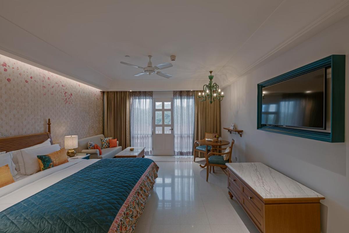 a bedroom with a large bed and a living room at Pilibhit House, Haridwar – IHCL SeleQtions in Haridwār