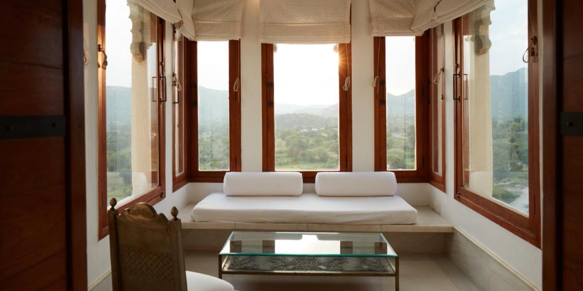 a window seat with a couch and a glass table at RAAS Devigarh in Udaipur