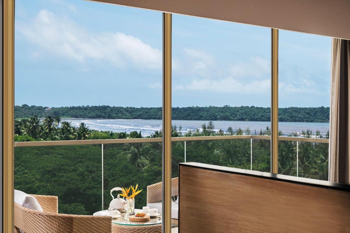 a room with a large window with a view of the water at Vivanta Goa, Miramar in Panaji a room with a large window with a view of the water at Vivanta Goa, Miramar in Panaji