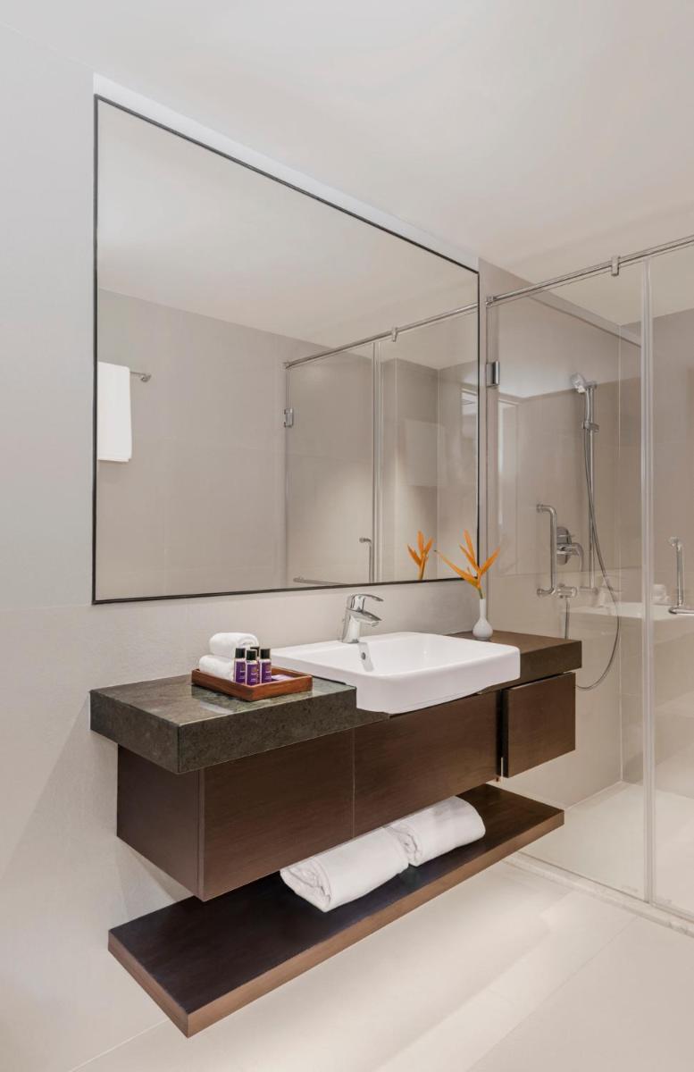 a bathroom with a sink and a large mirror at Vivanta Goa, Miramar in Panaji a bathroom with a sink and a large mirror at Vivanta Goa, Miramar in Panaji