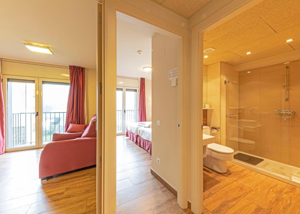 una habitación de hotel con una cama y un baño en Aparthotel Trainera, en Esterri d'Àneu