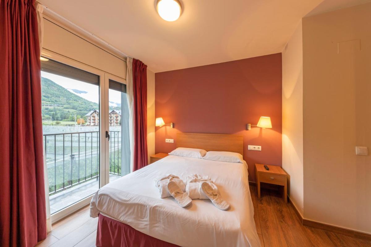 Un dormitorio con una cama y una ventana grande. en Aparthotel Trainera, en Esterri d'Àneu