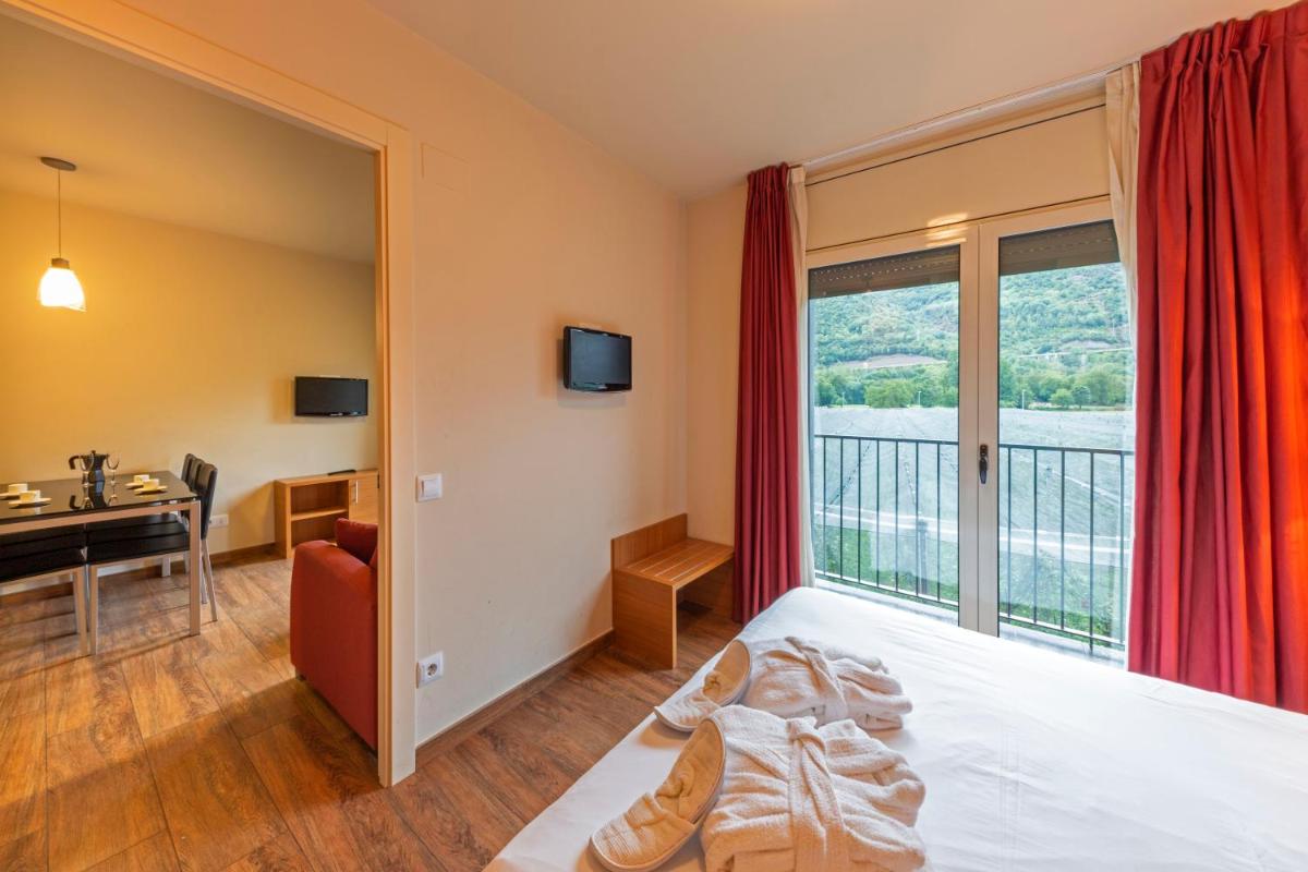 Una habitación de hotel con una cama, un escritorio y una ventana. en Aparthotel Trainera, en Esterri d'Àneu