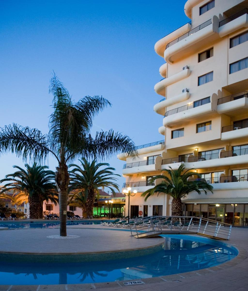 um hotel com palmeiras em frente a um prédio em Vila Gale Marina em Vilamoura