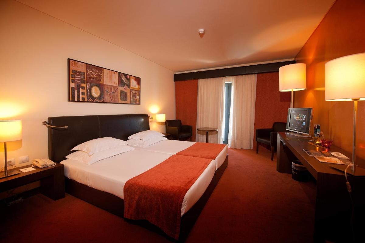um quarto de hotel com uma cama e uma escrivaninha em Vila Gale Santa Cruz em Santa Cruz - Madeira