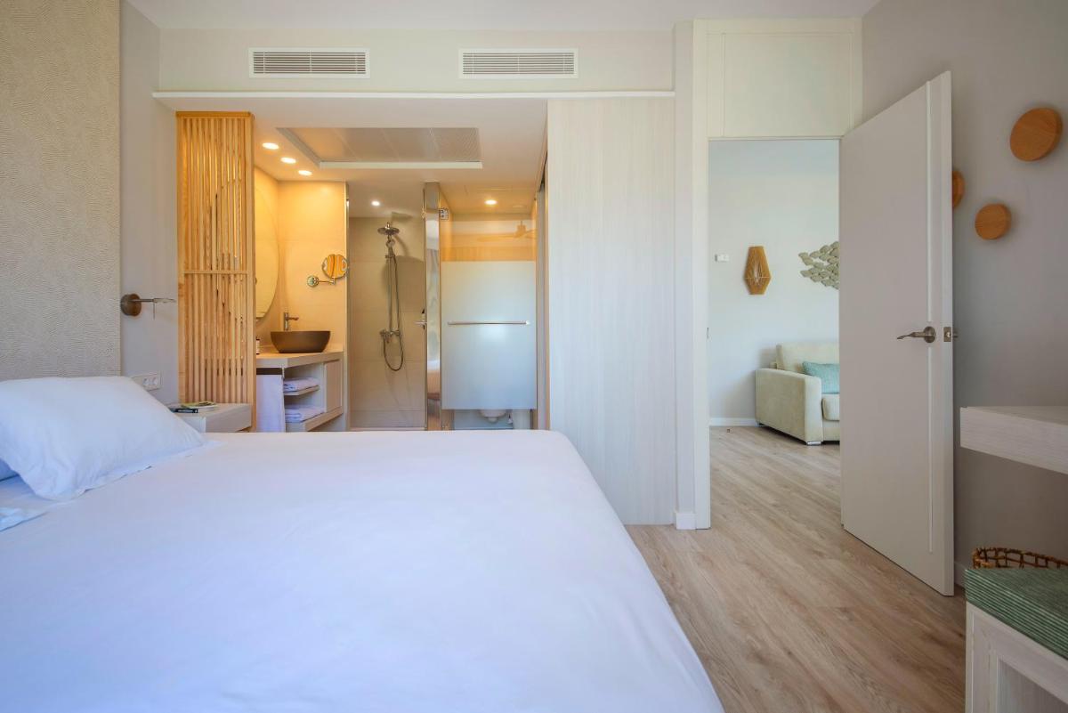 Un dormitorio con una cama blanca y un baño. en Blau Colònia Sant Jordi, en Colonia de Sant Jordi 85 fotos más