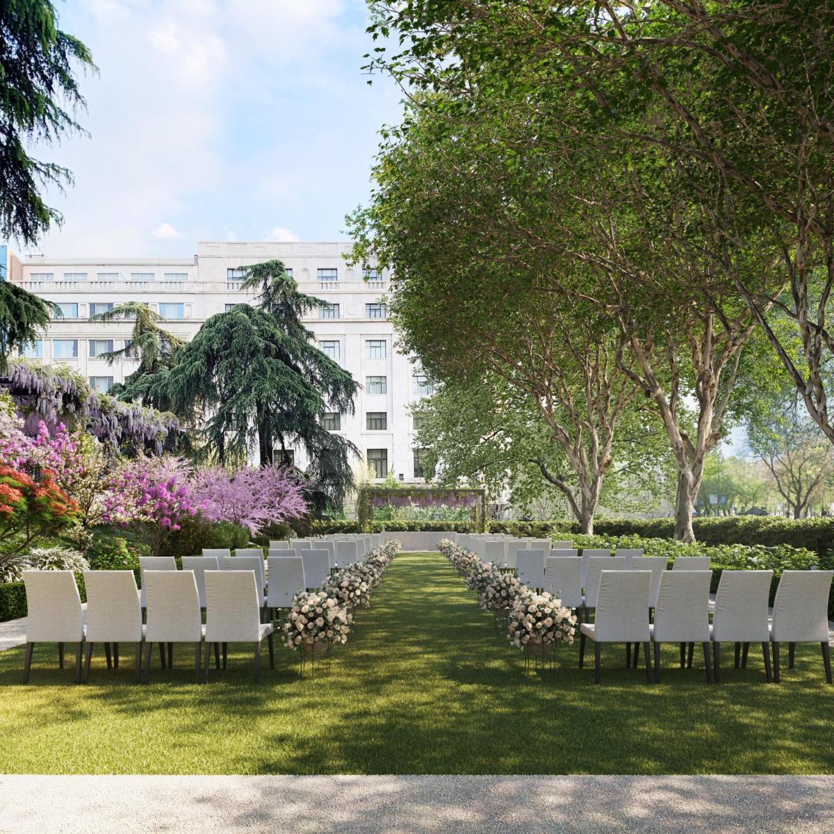 Una mesa larga con sillas blancas y flores frente a un edificio. en Rosewood Villa Magna, en Madrid