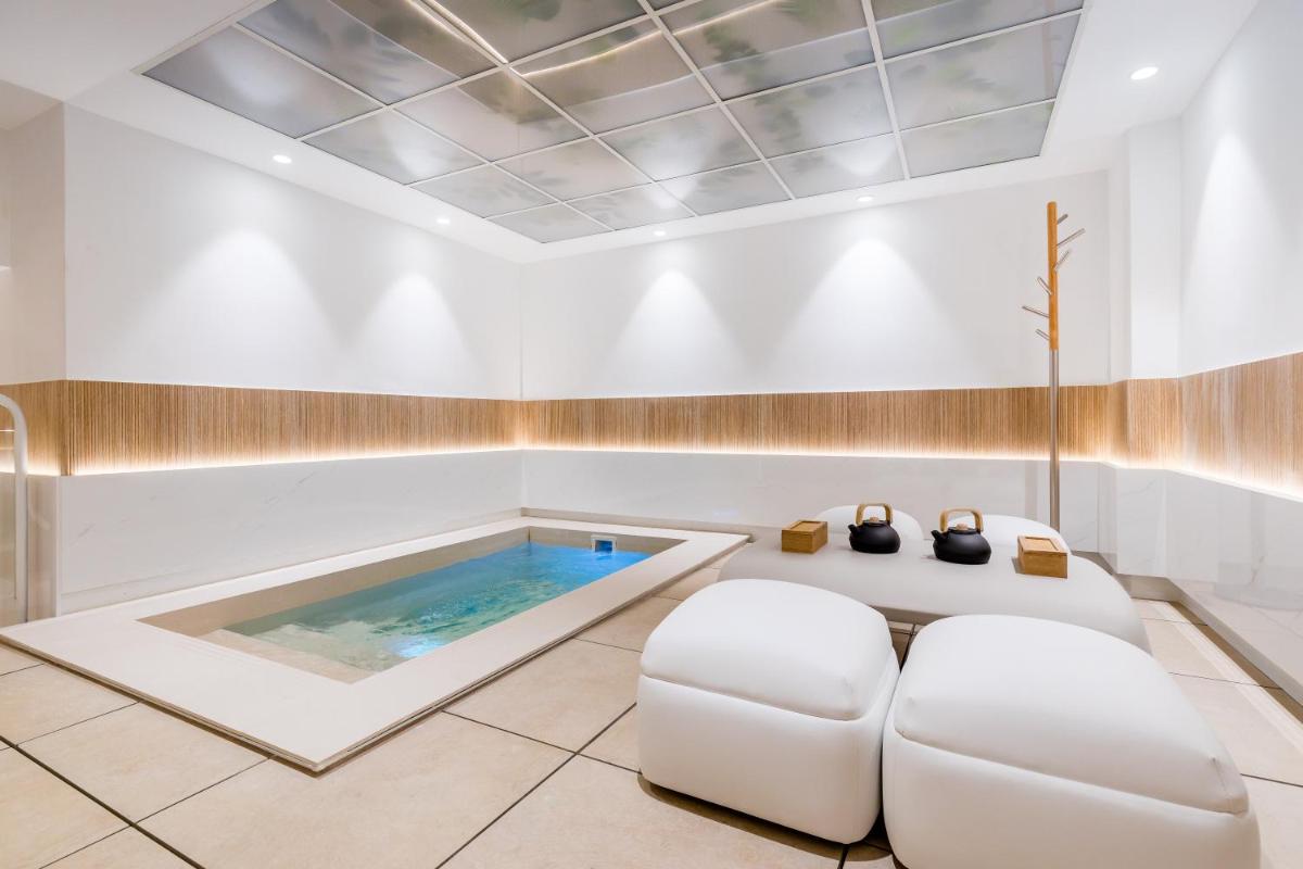 baño grande con bañera de hidromasaje y silla blanca en Barceló Marbella, en Marbella