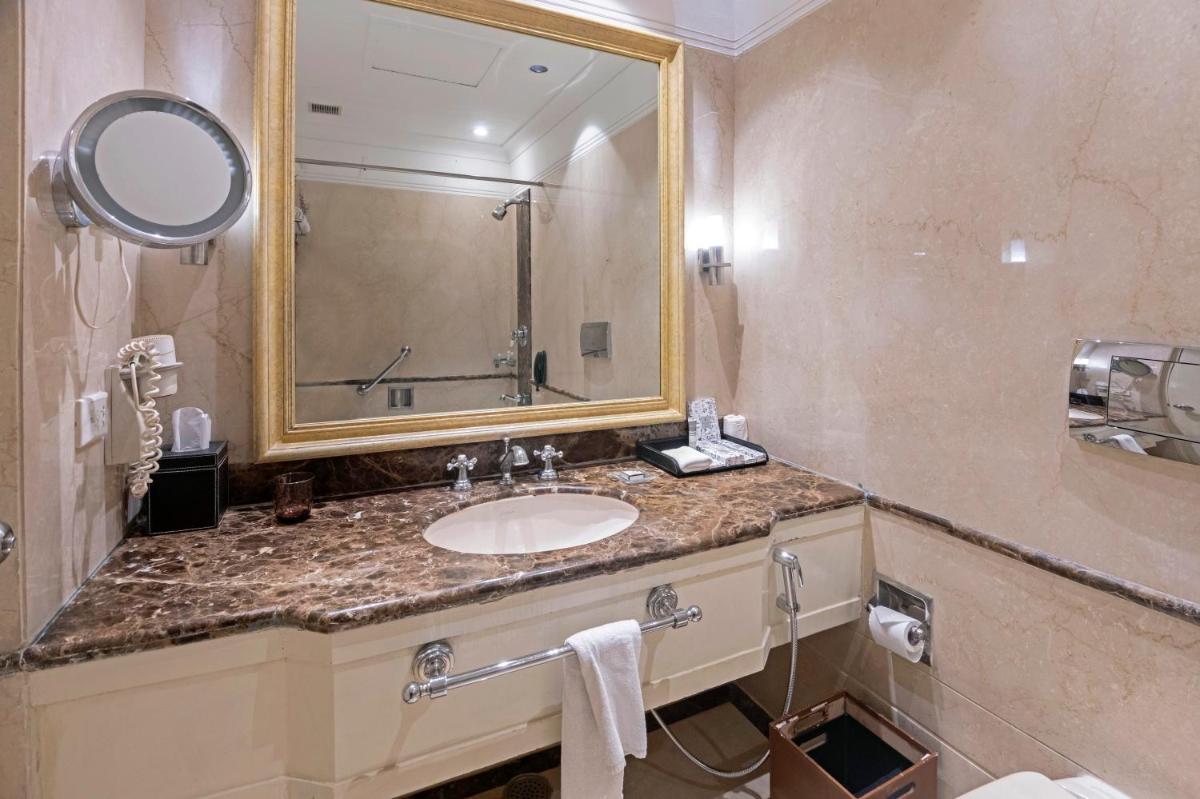 a bathroom with a sink and a mirror at The Claridges New Delhi in New Delhi a bathroom with a sink and a mirror at The Claridges New Delhi in New Delhi