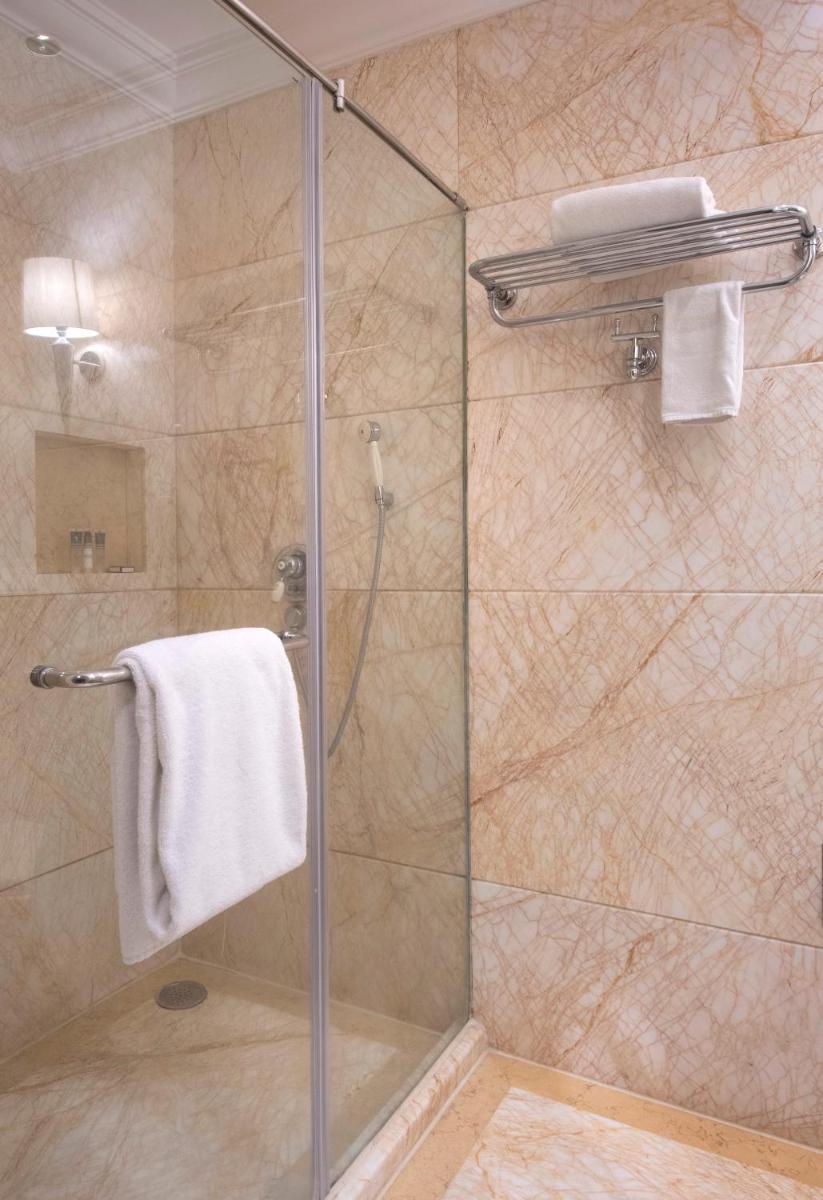 a bathroom with a shower with a glass door at The Claridges New Delhi in New Delhi a bathroom with a shower with a glass door at The Claridges New Delhi in New Delhi