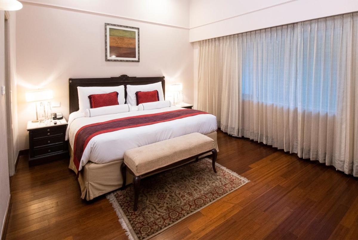 a bedroom with a large bed and a large window at The Claridges New Delhi in New Delhi a bedroom with a large bed and a large window at The Claridges New Delhi in New Delhi