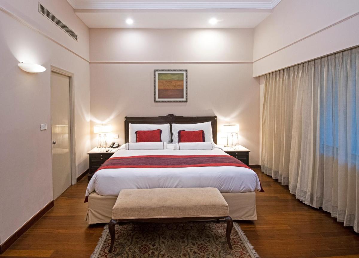 a bedroom with a large bed with red pillows at The Claridges New Delhi in New Delhi a bedroom with a large bed with red pillows at The Claridges New Delhi in New Delhi