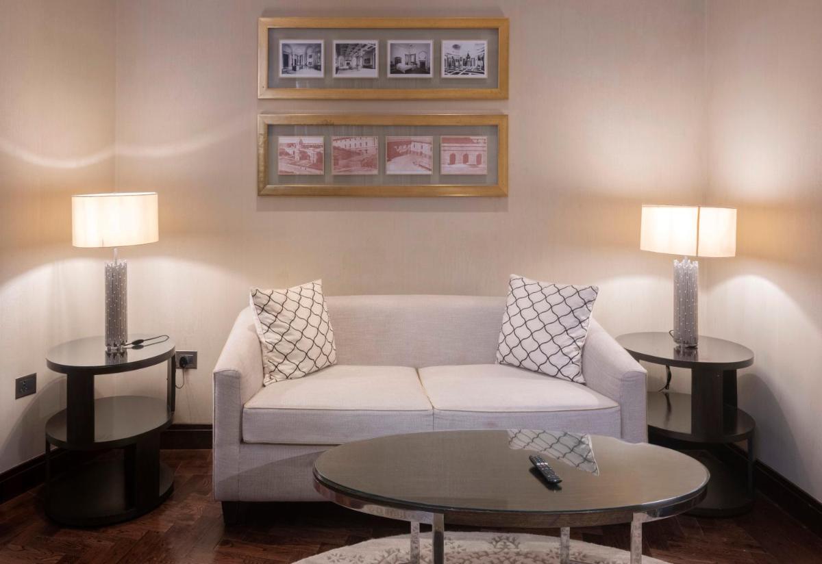 a living room with a couch and two tables at The Claridges New Delhi in New Delhi a living room with a couch and two tables at The Claridges New Delhi in New Delhi