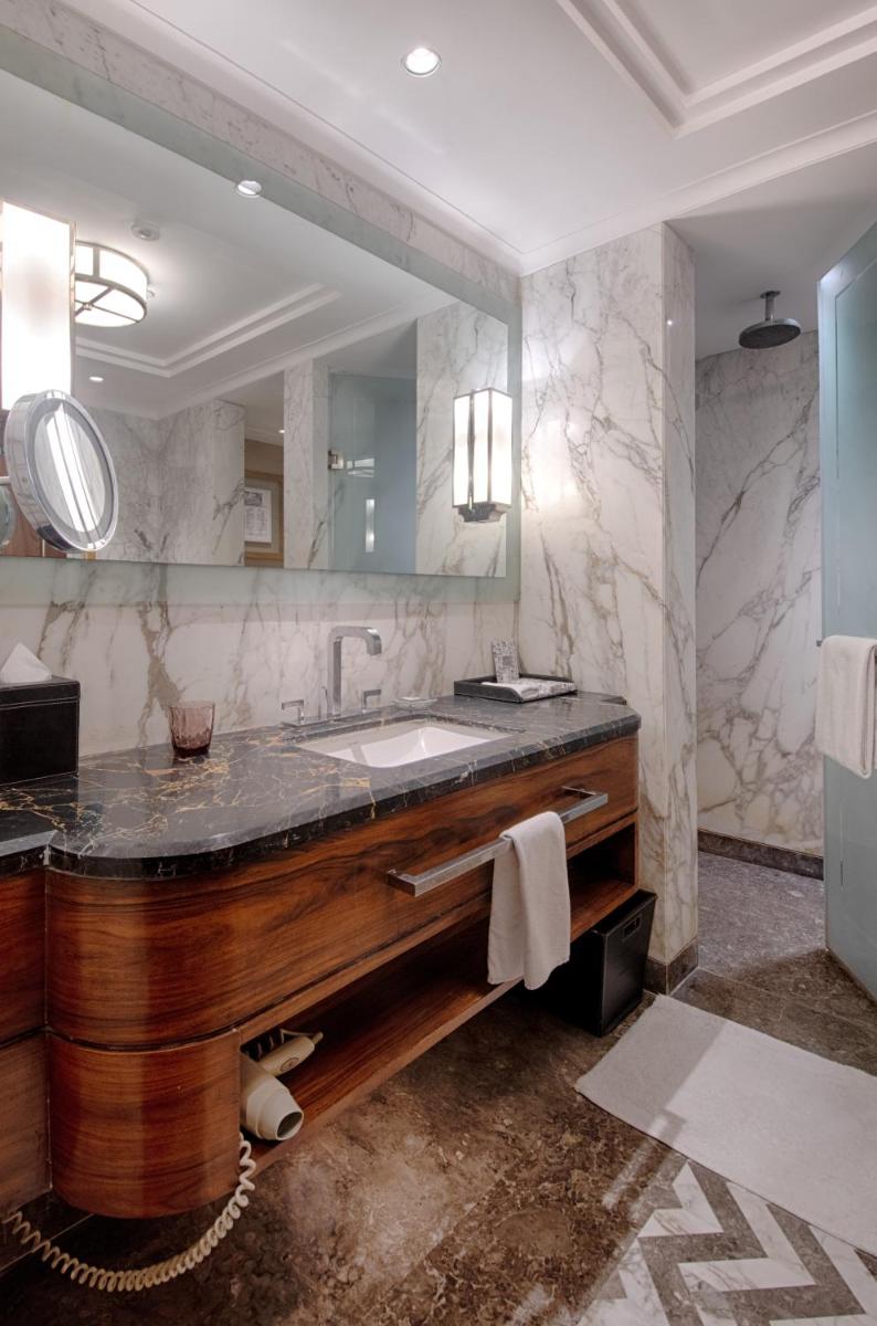 a bathroom with a sink and a large mirror at The Claridges New Delhi in New Delhi a bathroom with a sink and a large mirror at The Claridges New Delhi in New Delhi