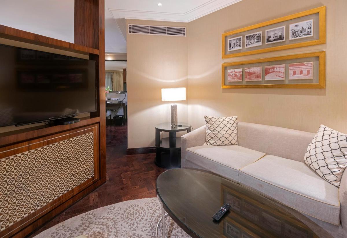 a living room with a couch and a flat screen tv at The Claridges New Delhi in New Delhi a living room with a couch and a flat screen tv at The Claridges New Delhi in New Delhi