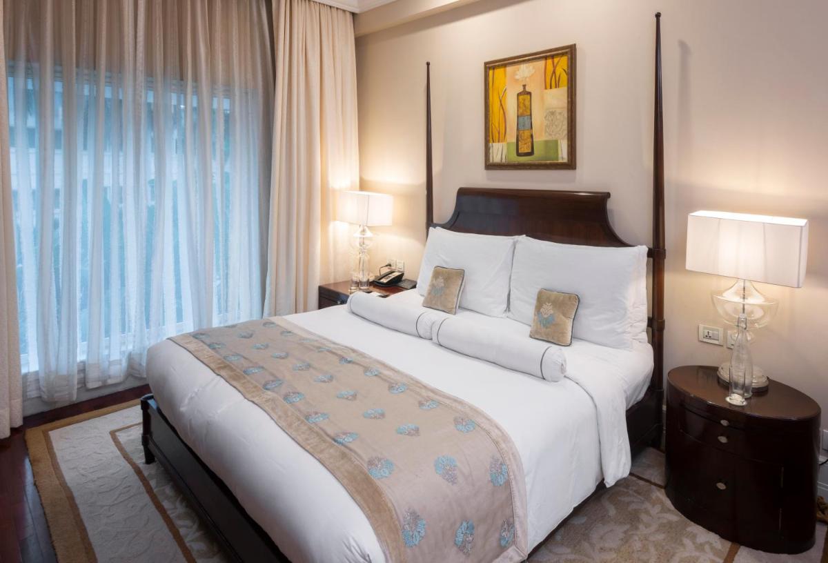 a bedroom with a large white bed with two lamps at The Claridges New Delhi in New Delhi a bedroom with a large white bed with two lamps at The Claridges New Delhi in New Delhi