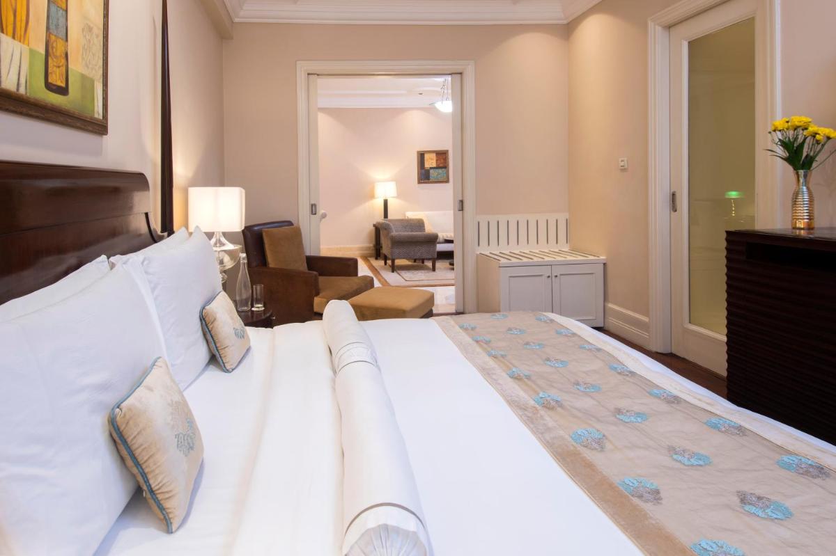 a bedroom with a large bed and a living room at The Claridges New Delhi in New Delhi a bedroom with a large bed and a living room at The Claridges New Delhi in New Delhi