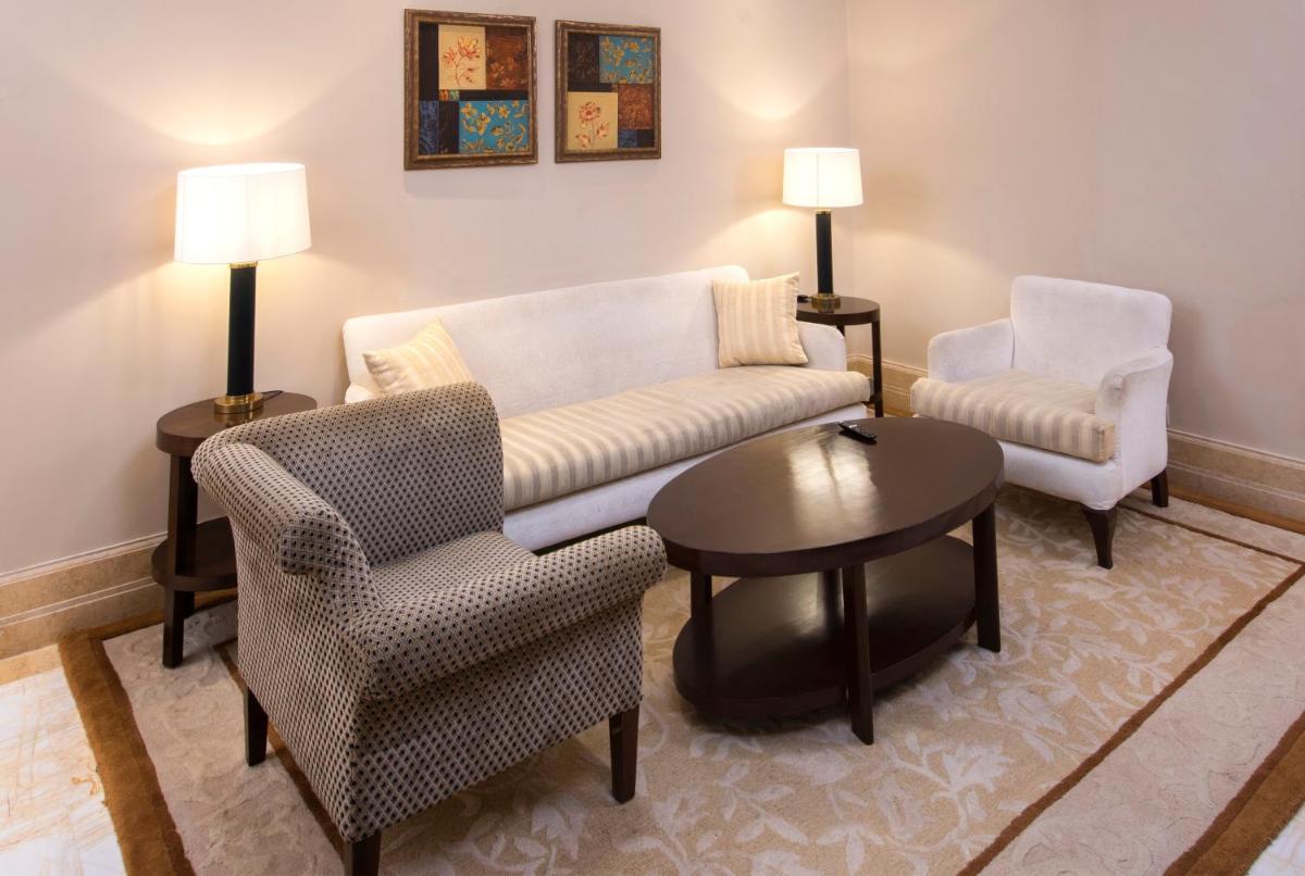 a living room with a couch and two chairs and a table at The Claridges New Delhi in New Delhi a living room with a couch and two chairs and a table at The Claridges New Delhi in New Delhi