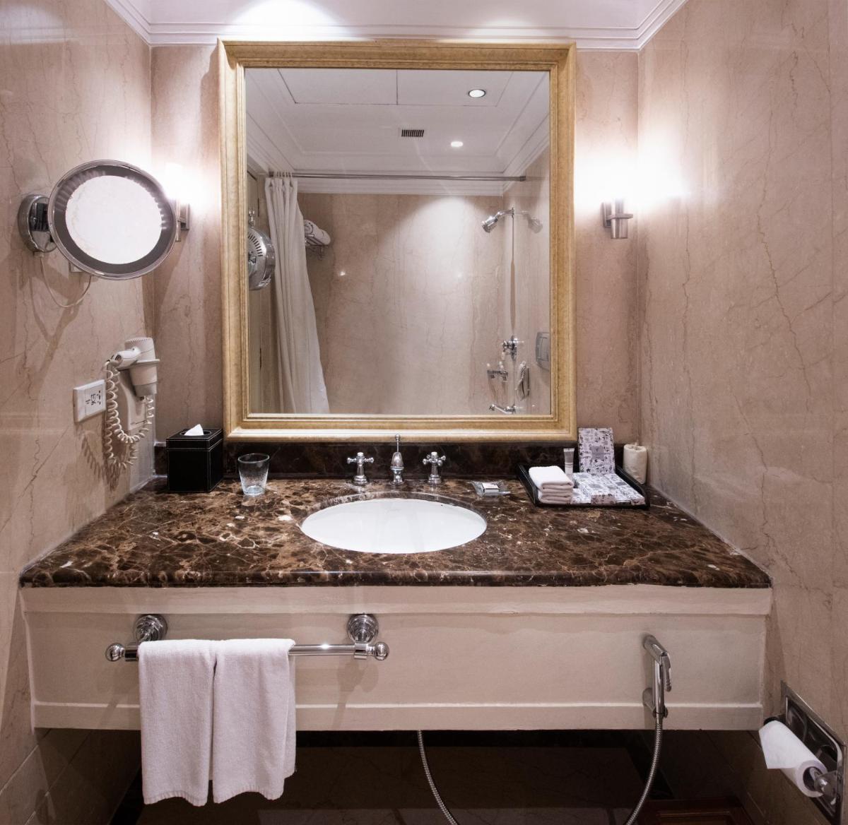a bathroom with a sink and a mirror at The Claridges New Delhi in New Delhi a bathroom with a sink and a mirror at The Claridges New Delhi in New Delhi
