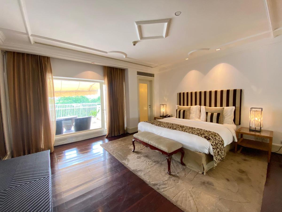 a bedroom with a large bed and a large window at The Claridges New Delhi in New Delhi a bedroom with a large bed and a large window at The Claridges New Delhi in New Delhi