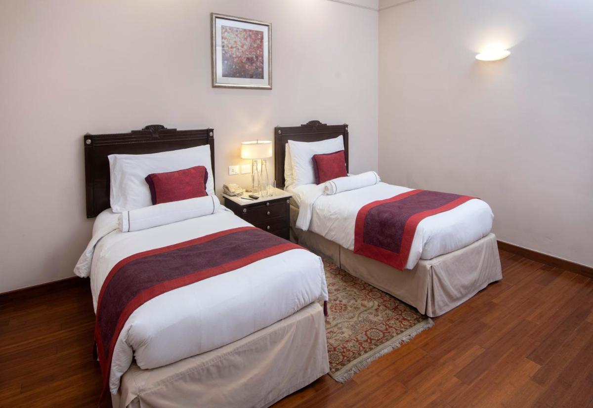 a hotel room with two beds in a room at The Claridges New Delhi in New Delhi a hotel room with two beds in a room at The Claridges New Delhi in New Delhi