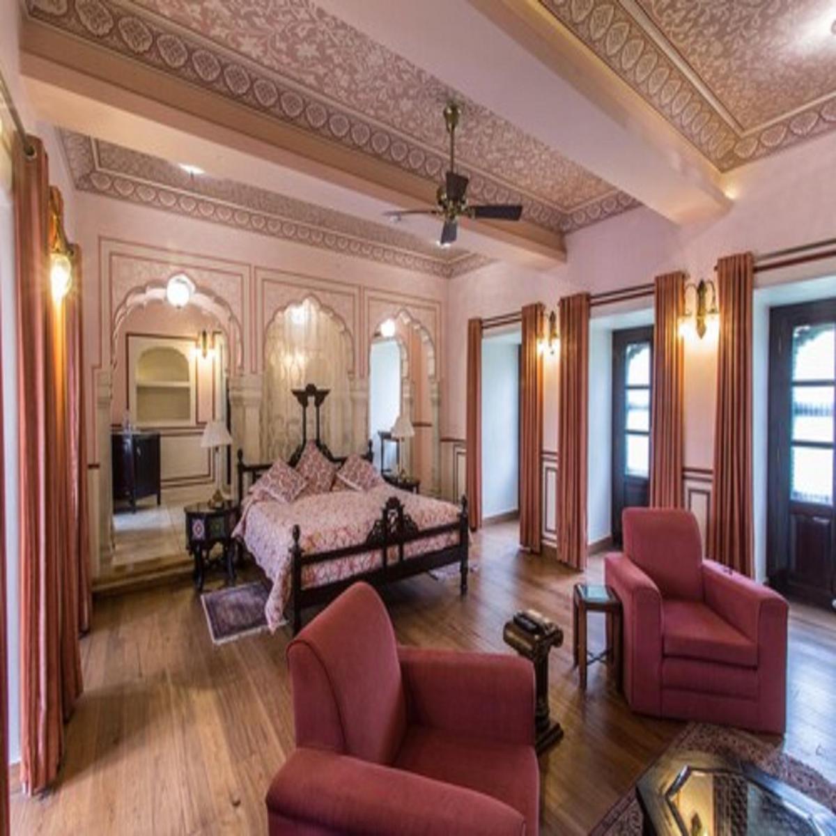 a large bedroom with a bed and two chairs at Royal Heritage Haveli - By Leisure Hotels in Jaipur
