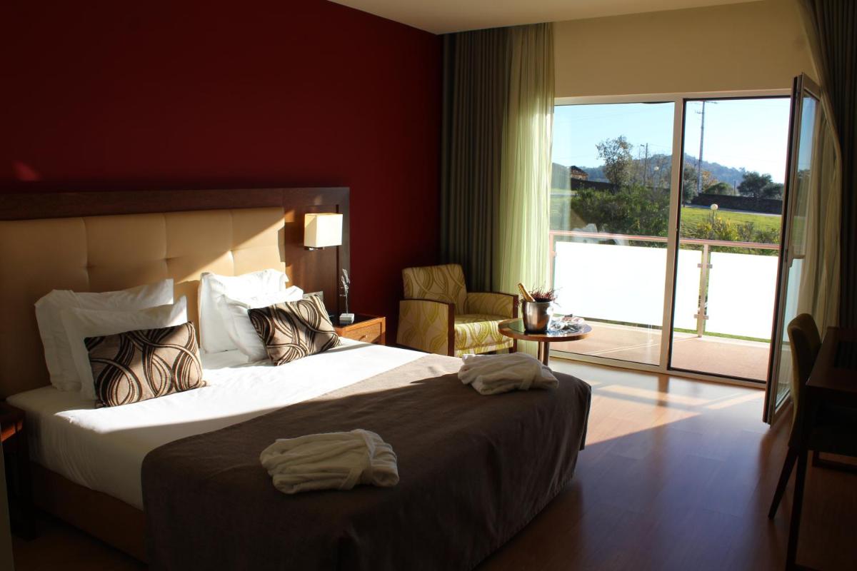 um quarto de hotel com uma cama e uma janela grande em Palace Hotel & Spa Termas de São Tiago em Penamacor