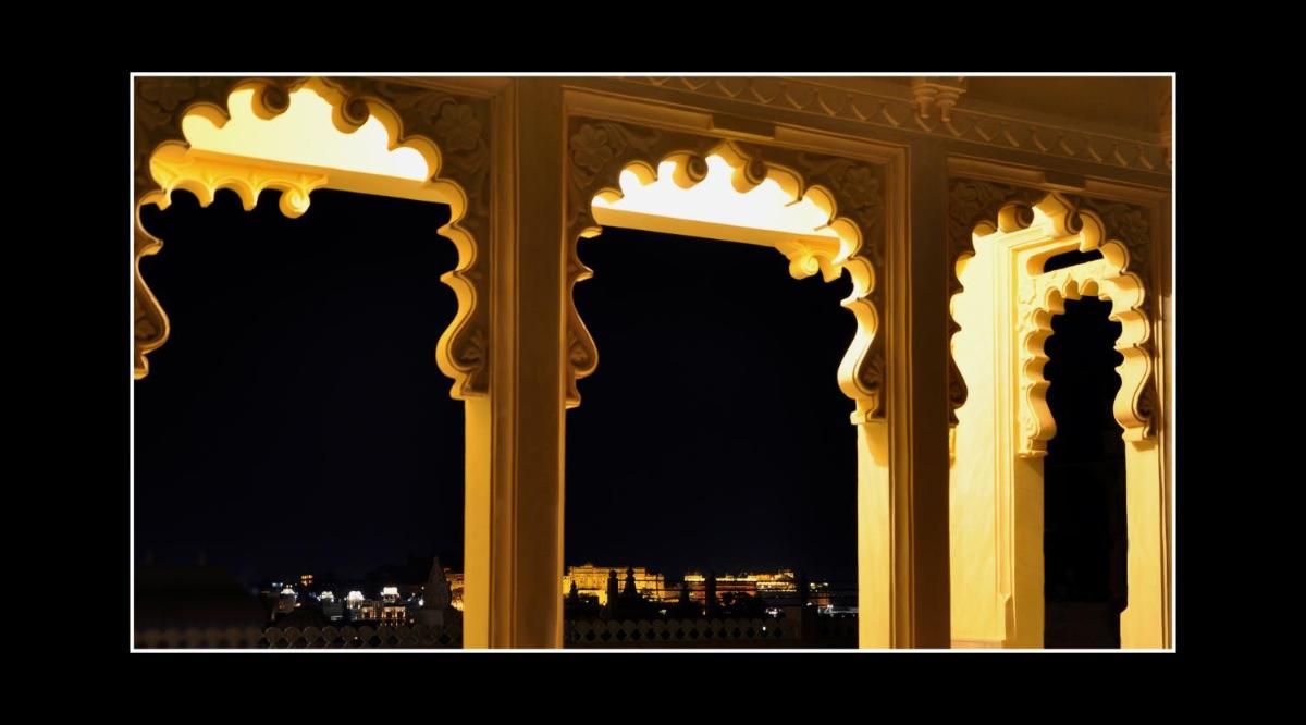 an archway with a view of a city at night at Chunda Palace in Udaipur