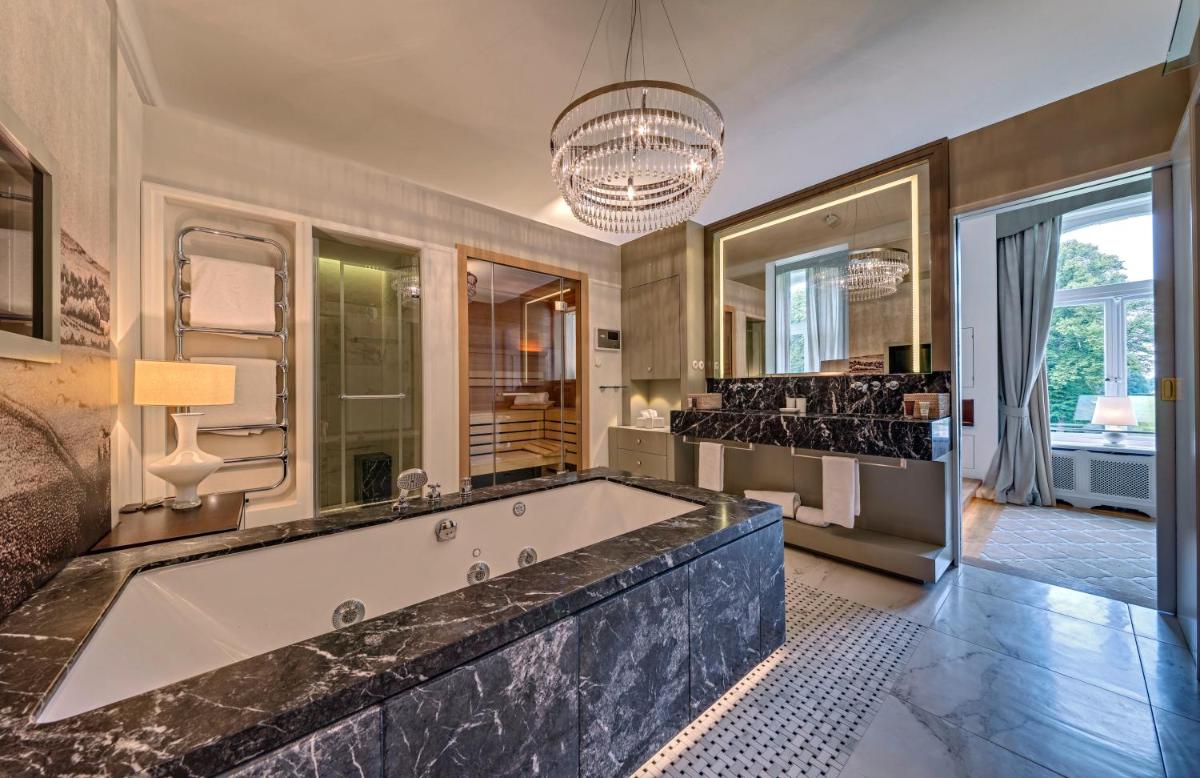 ein Badezimmer mit großer Badewanne und großem Spiegel in der Unterkunft Weissenhaus Private Nature Luxury Resort in Weißenhaus