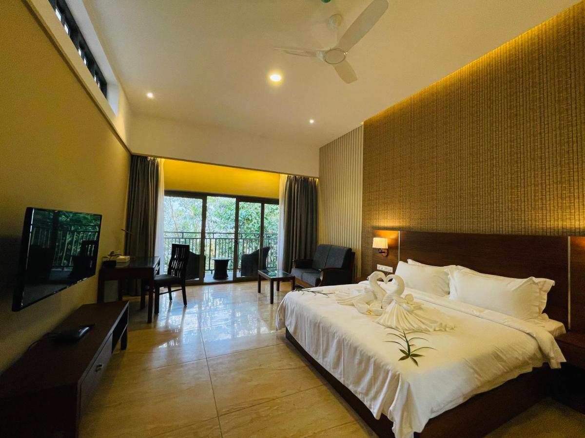 a bedroom with a large white bed and a television at Elephant Passage in Munnar