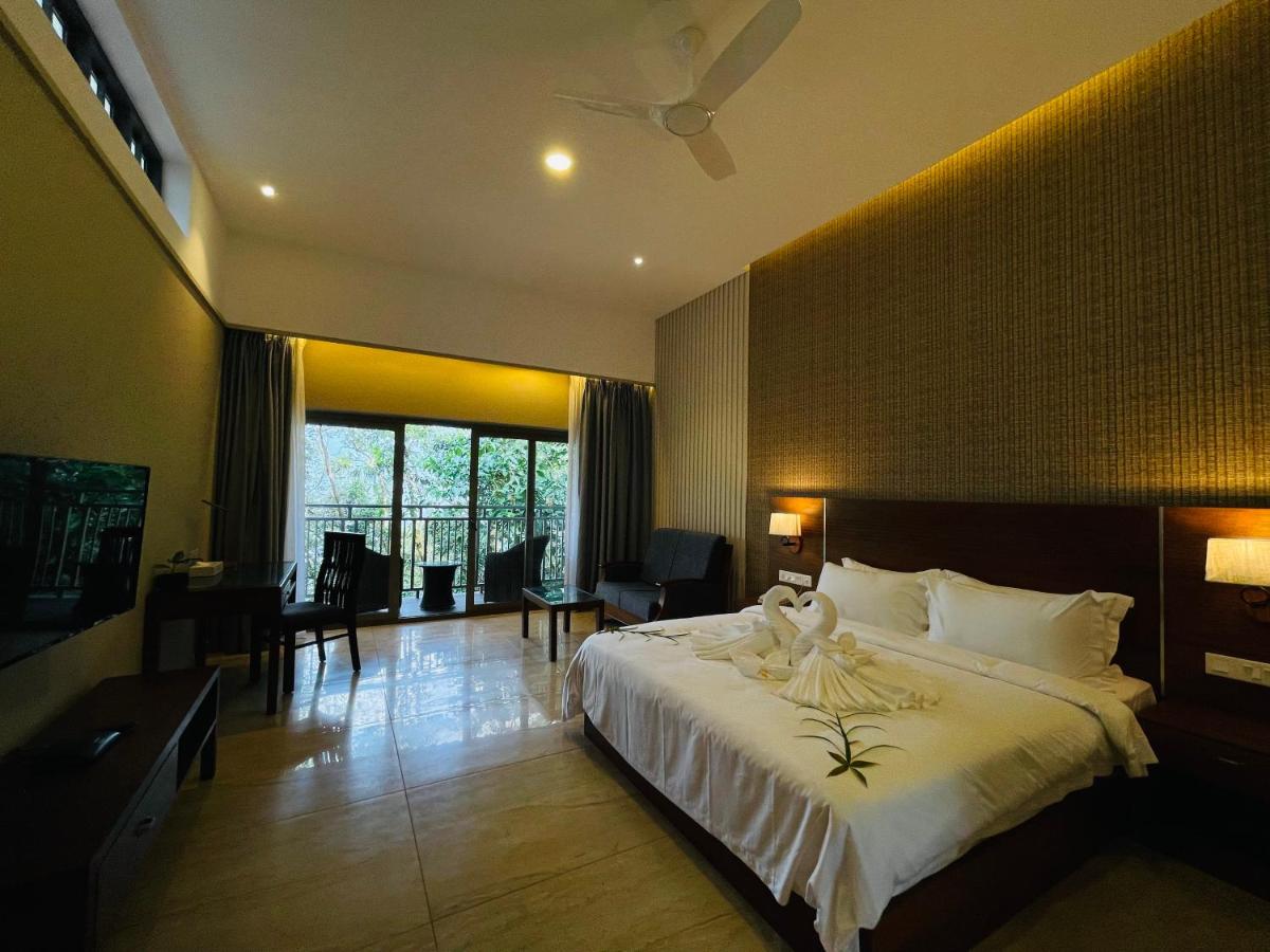 a bedroom with a large bed and a living room at Elephant Passage in Munnar