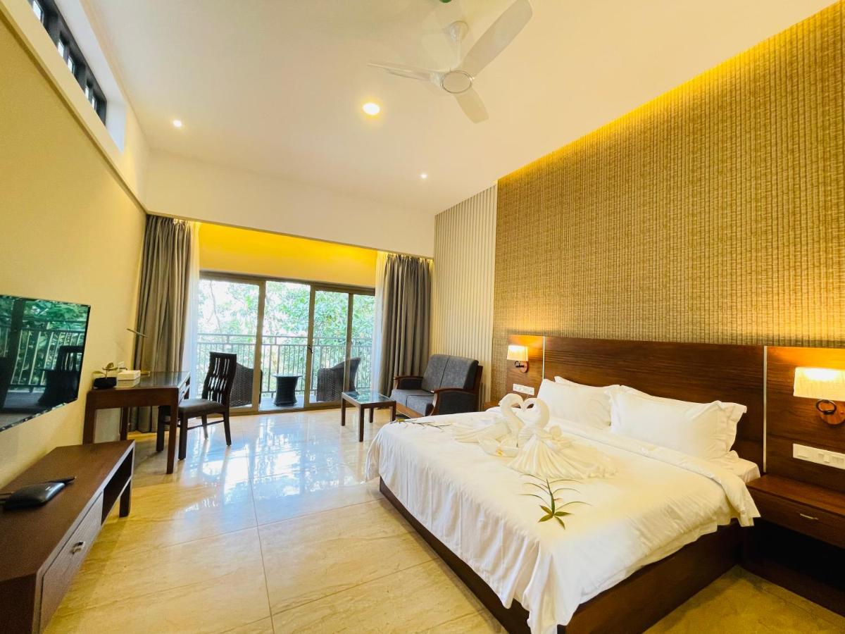 a bedroom with a large white bed and a desk at Elephant Passage in Munnar