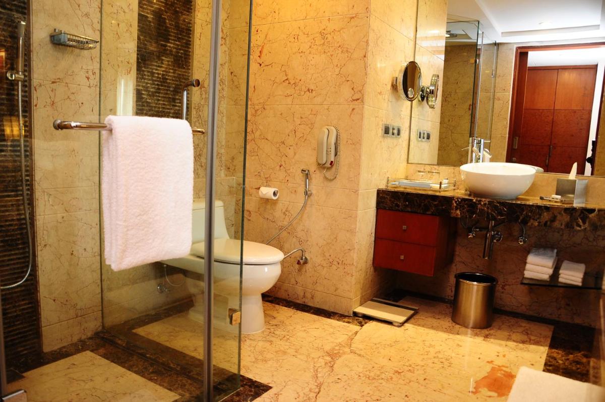 a bathroom with a toilet and a sink and a shower at Radisson Blu Plaza Delhi Airport in New Delhi a bathroom with a toilet and a sink and a shower at Radisson Blu Plaza Delhi Airport in New Delhi