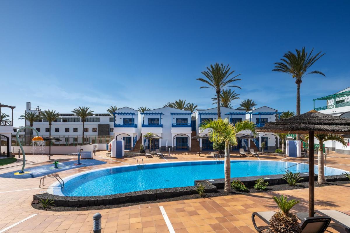 una piscina con palmeras y edificios en Hotel Mirador Papagayo by LIVVO, en Playa Blanca