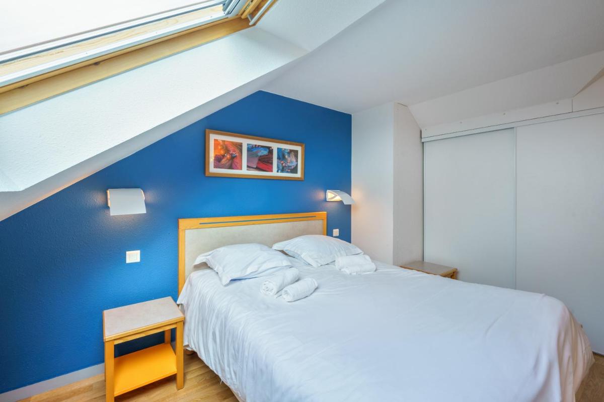 un lit dans une chambre avec un mur bleu dans l'établissement Résidence Pierre & Vacances la Corniche de la Plage, à Bénodet