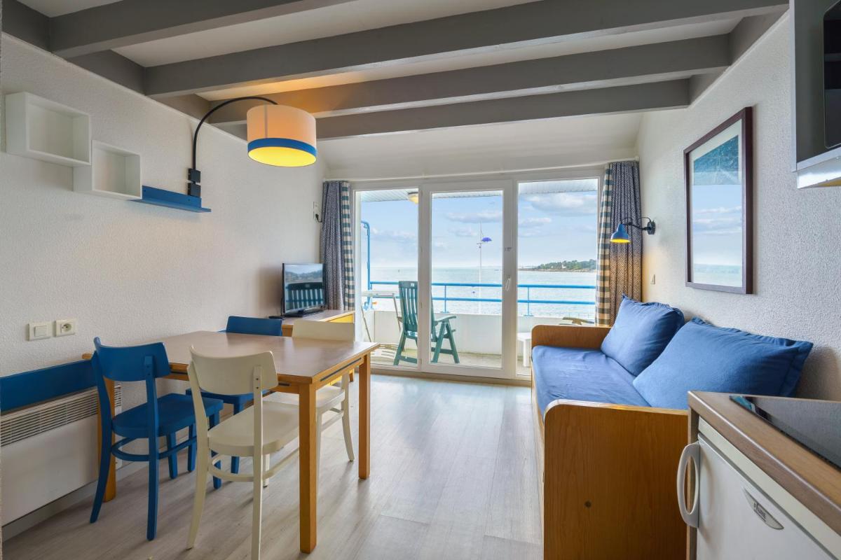 Il comprend une cuisine et un salon avec une table et un canapé bleu. dans l'établissement Résidence Pierre & Vacances la Corniche de la Plage, à Bénodet