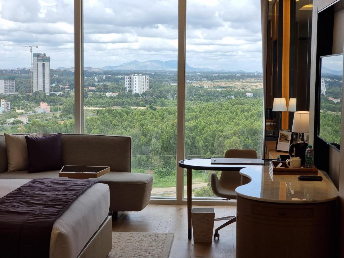 a room with a bed and a table and a large window at The Leela Bhartiya City Bengaluru in Bengaluru a room with a bed and a table and a large window at The Leela Bhartiya City Bengaluru in Bengaluru