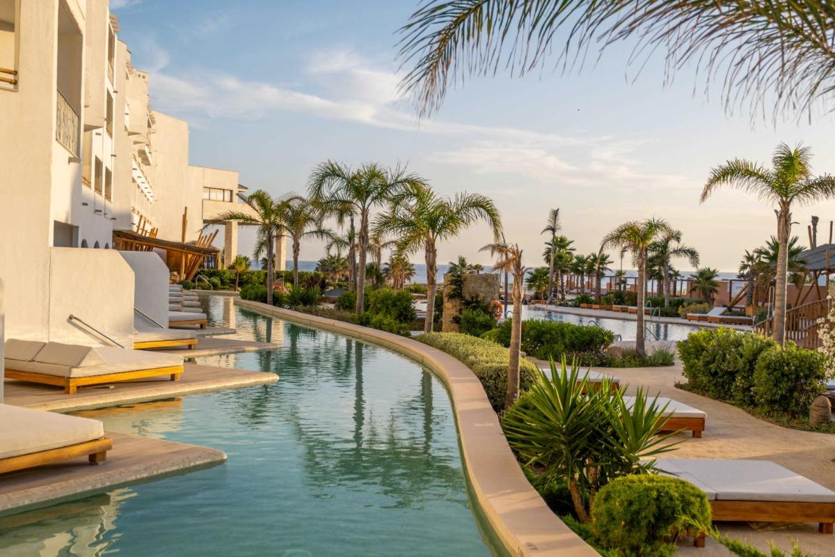 una piscina en un resort con palmeras en Zahara Beach & Spa by QHotels - Adults Recommended, en Zahara de los Atunes