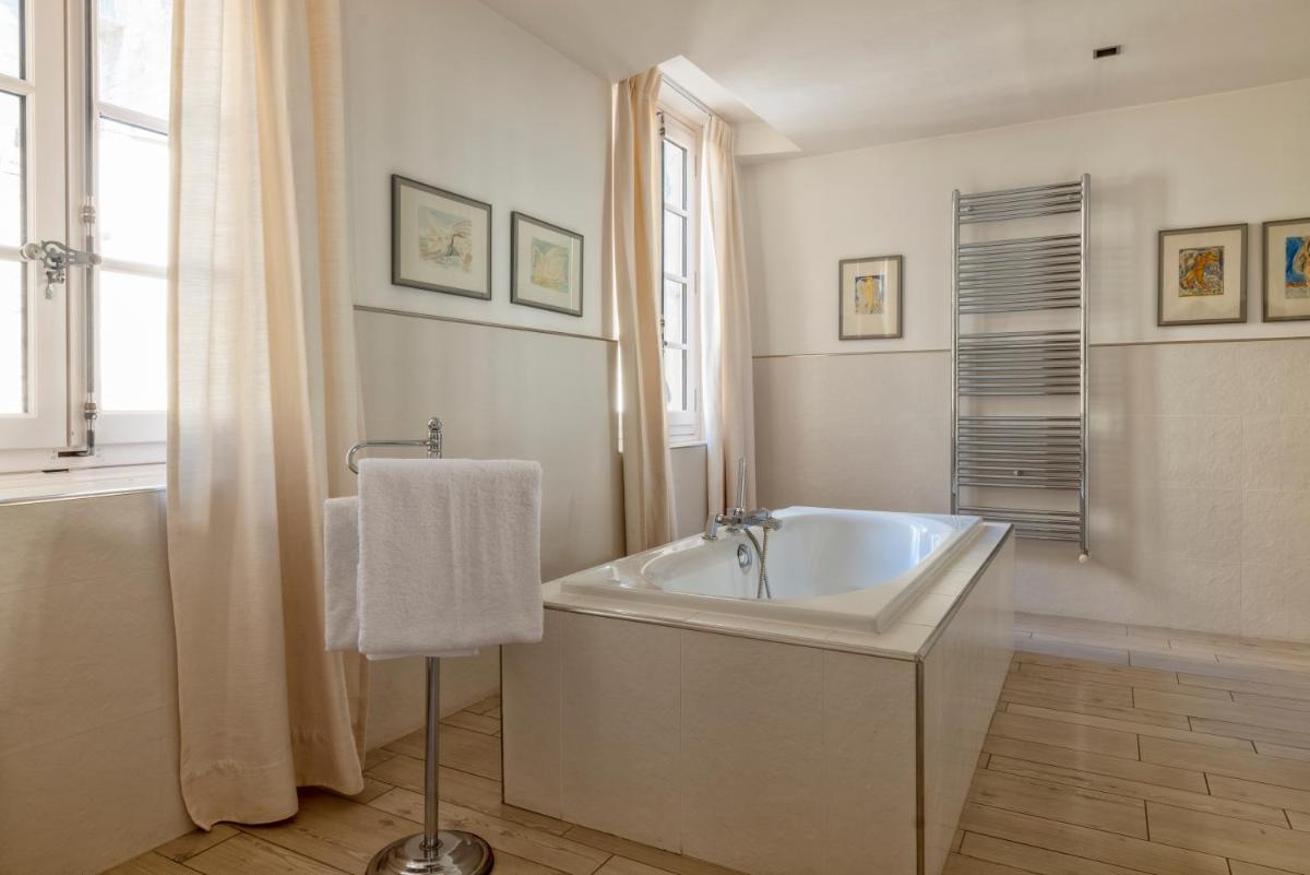 La salle de bains blanche est pourvue d'une baignoire et d'une fenêtre. dans l'établissement Le Prieure, à Villeneuve-lès-Avignon 29 autres photos