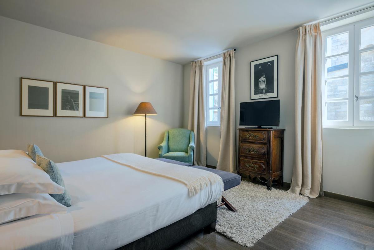 une chambre avec un lit, une télévision et une chaise dans l'établissement Le Prieure, à Villeneuve-lès-Avignon
